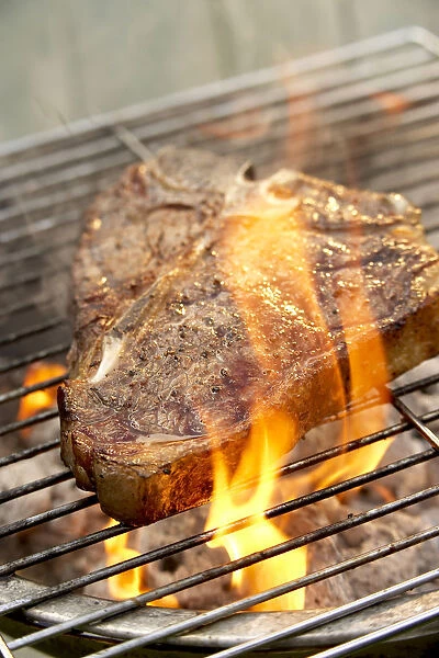 Fire flaring up around steak on barbecue grill