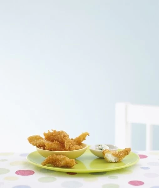 Fish goujons in bowl on plate with tartare sauce