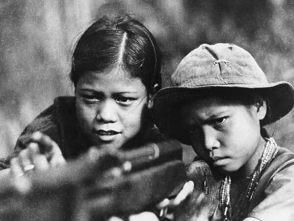 A fourteen year old viet cong girl teaching her younger brother to fire a rifle, thua thien province, south vietnam, 1968, vietnam war