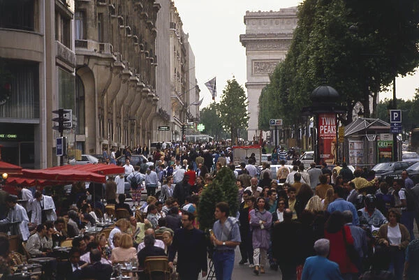 France, Paris, Avenue des Champs Elysees, with l Arc de Triomphe obscured behind the trees, crowded street scene