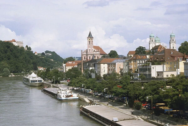 Germany, Bavaria, the beautiful town of Passau, on the river Danube. The river is lined with industrial barges, a passenger boat, with the onion domes of Dom St Stephen in the background