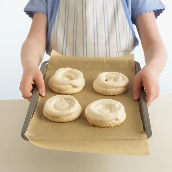 Girl holding baked meringues on baking tray