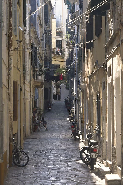 Greece, Corfu, Corfu town, narrow residential street lined with scooters and bicycles