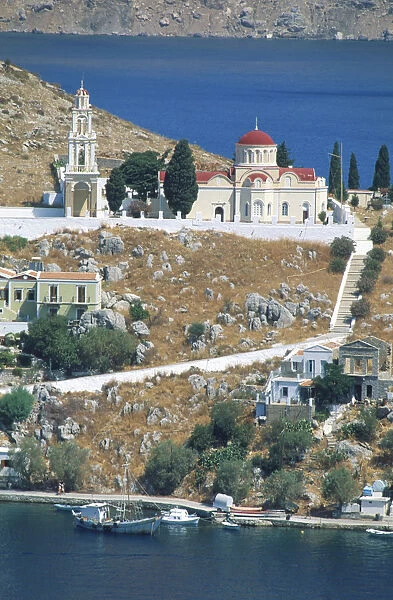 Greece, Dodecanese islands, Saegean, rocky hillside with church, boats moored, blue sea in foreground and background
