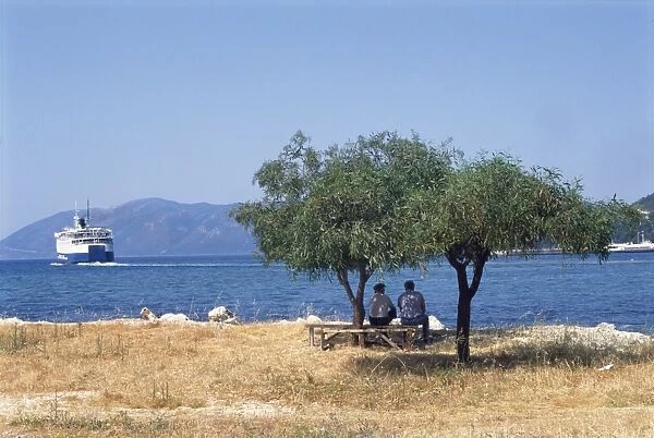 Greece, Kefallonia, Sami town, large ship approaching land, two men sitting in shade of tree