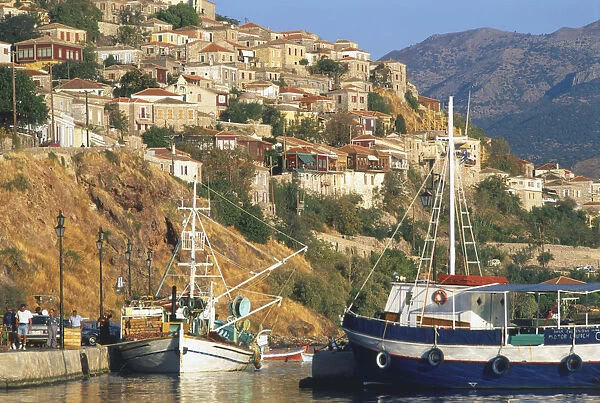 Greece, Lesvos, Molyvos, tiered stone houses rising above picturesque harbour, fishing boats moored in foreground