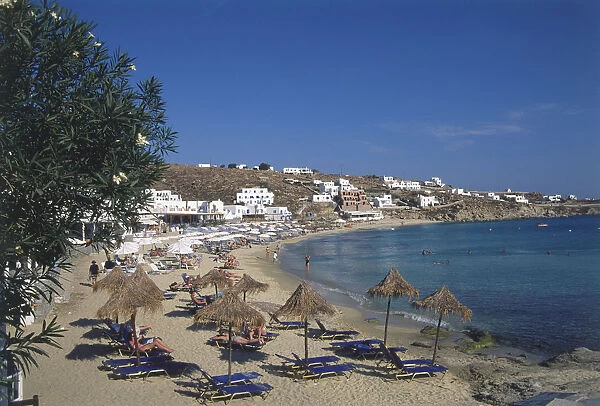Greece, Mykonos, Platys Gialos beach, people laying under beach umbrellas and in the sea