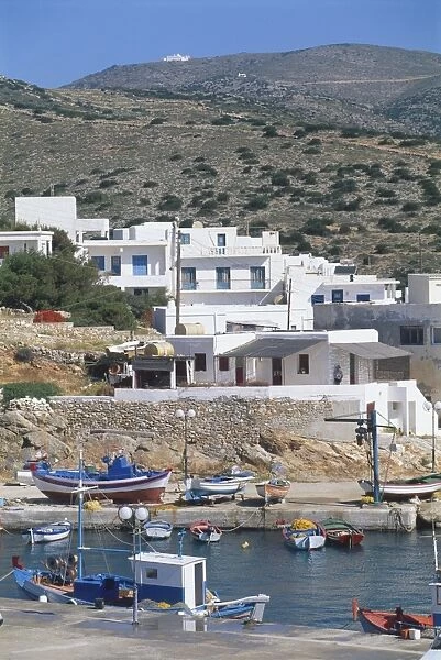 Greece, Sikinos, whitewashed houses perched on hills above Alopronoia port, small boats moored, hills in background