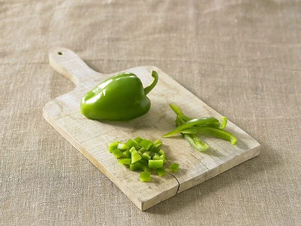 Green pepper on chopping board, chopped and sliced