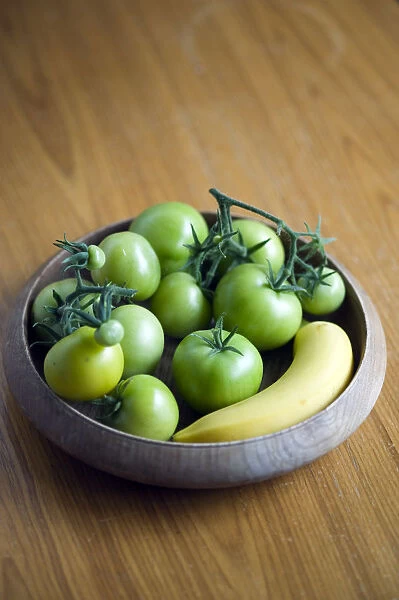 Green tomatoes in bowl next to banana