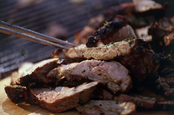 Grilled meat and barbecue tongs, close-up