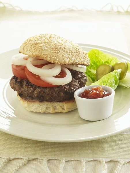Hamburger stuffed with onions and tomatoes, served with salad garnish and bowl of fresh tomato ketchup, close-up