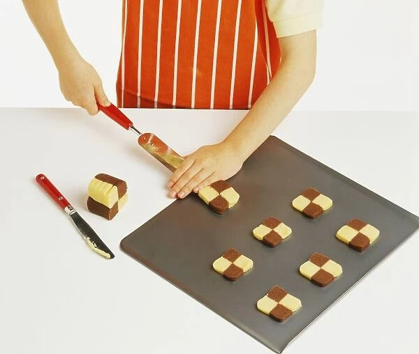 Hand model wearing orange and white striped apron, placing chocolate and plain shortbread dough