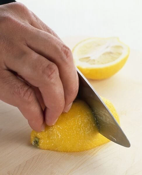 Hand shown slicing a lemon with a sharp knife, close-up
