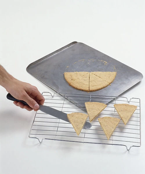 Hazelnut pastry triangles being transferred from a baking tray onto a wire rack, using a palette knife or spatula