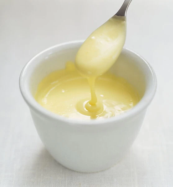 Hollandaise sauce being spooned from small bowl, close up