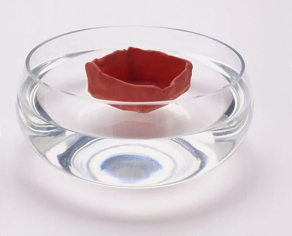 A hollowed out piece of plasticine shaped as a bowl floating in a bowl of water