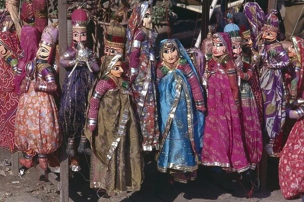 India, Sireh Deori Bazaar, brightly coloured puppets for sale, wearing brightly coloured traditional Indian dress, female puppets wearing vivid saris, male puppets with large black moustache, hanging by red string