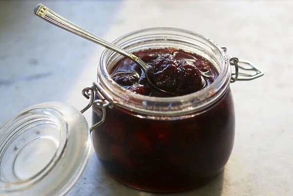 Jar of strawberry jam with spoon, close-up