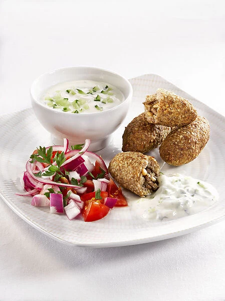 Kibbeh with salad and savoury sauce in plate, close-up