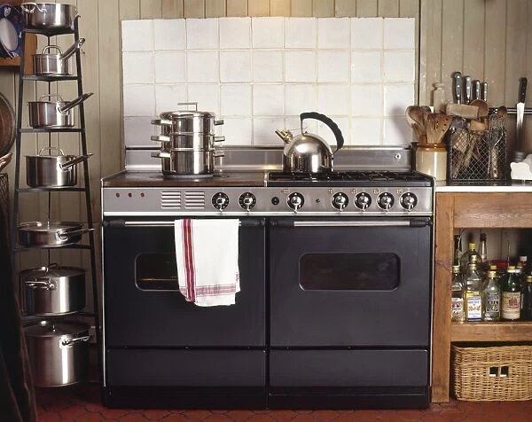 Kitchen oven and hob unit with stainless steel kettle and steamer on top, pan shelving