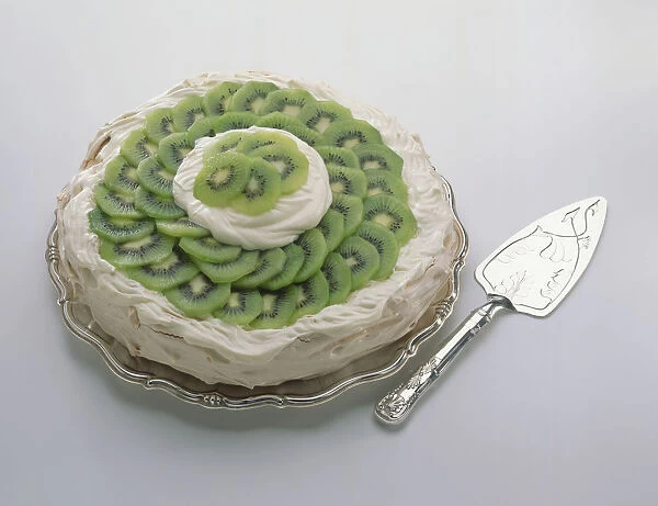Kiwi fruit pavlova on silver platter, and a silver cake server