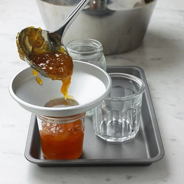 Ladling marmalade through funnel into jar