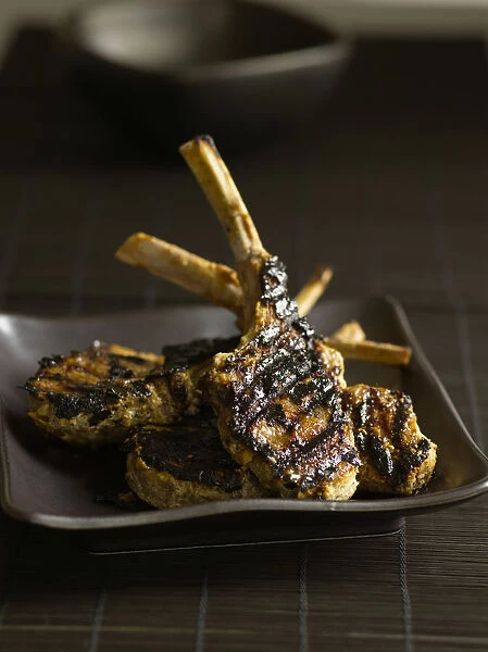 Lamb lollipops, marinated and grilled lamb rib chops, on brown plate