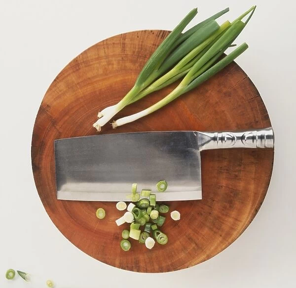 Large blade, spring onions and rings on chopping board, overhead view