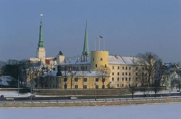 Latvia, Riga Historic Centre, castle on frozen Dvina (Daugava) river waterfront, St Jamess Cathedral spire, view from suspension Vansu Bridge