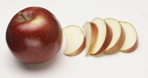 Malus domestica, a whole Apple with slices of on the side