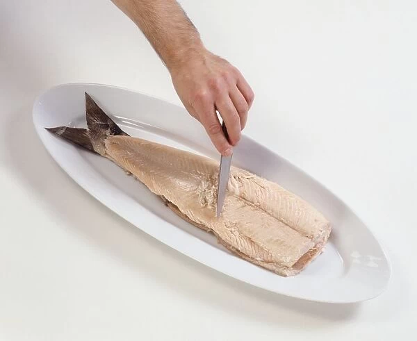 Man boning poached salmon with chefs knife, close-up
