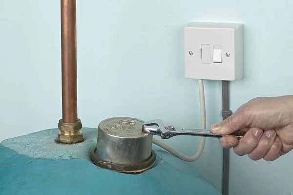 Man using adjustable spanner to remove nut on boiler cover, plug switched off, close-up