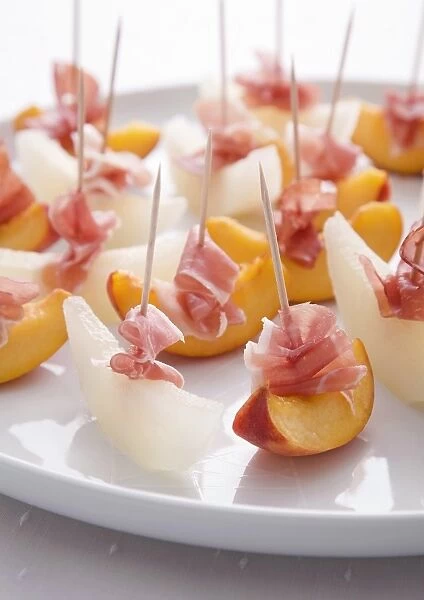 Melon and peaches with prosciutto on plate, close-up