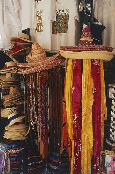 Mexico, straw hats and brightly coloured scarves in a street market souvenir stall