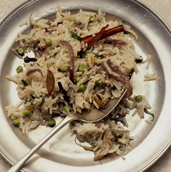 Mutter pulao served on metal plate with spoon, close up