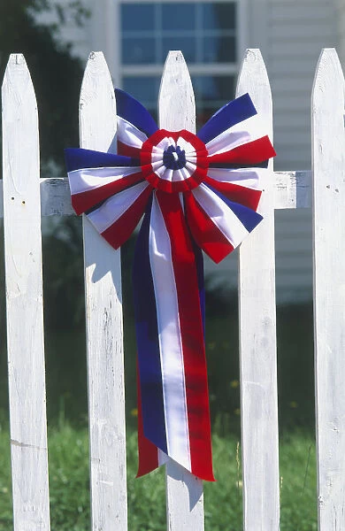 New England, Fourth of July red white and blue rosette on white picket fence, close-up