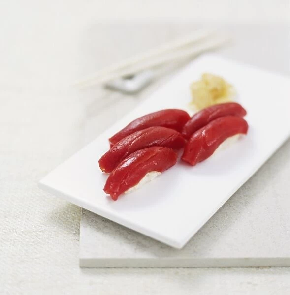 Nigiri sushi parcels made from rice topped with raw tuna slices, on a white board, high angle view