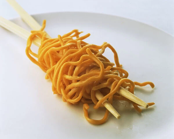 Noodles wrapped around chopsticks on a plate