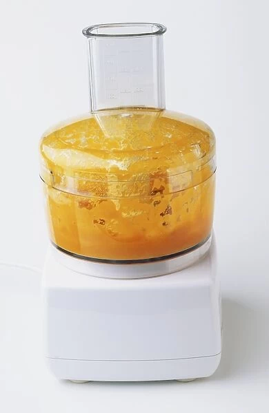 Orange mixture splashed inside food processor container, side view