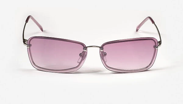 Pair of rose tinted square framed sunglasses on white surface