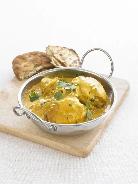 Pan of Chicken Tikka Masala, garnished with coriander leaves, served with naan bread