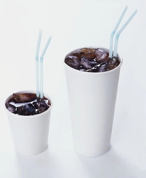 Two paper cups of iced cola with straws