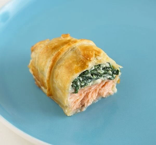 Pastry parcel stuffed with salmon and spinach on a blue plate