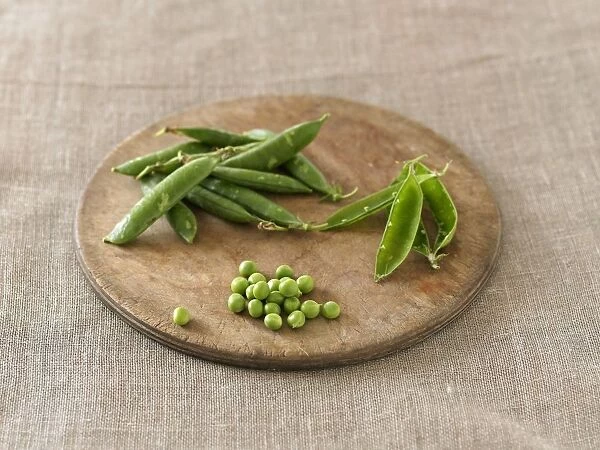 Pea pods and green peas on chopping board