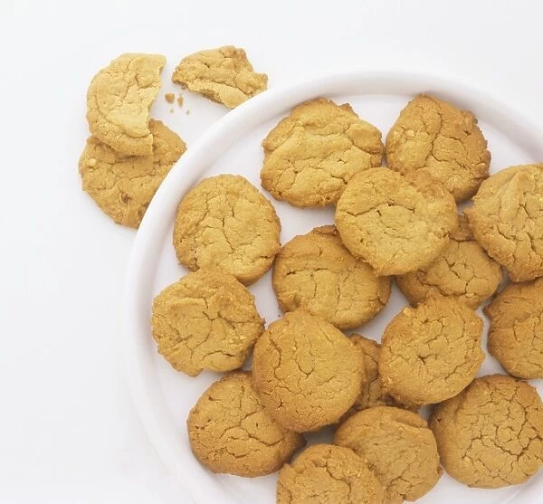 Peanut butter cookies on a white plate, with a couple of cookies on the side broken in half
