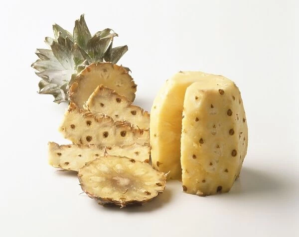 Peeled pineapple with section removed displayed next to its skin, close up