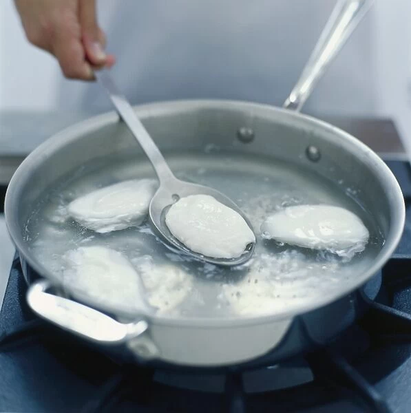 Person lifting poached egg from simmering water with slotted spoon