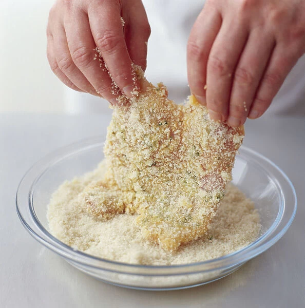 Person turning chicken escalopes in breadcrumbs, close-up