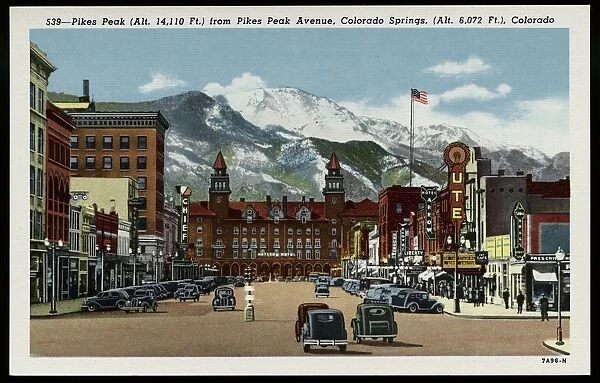 Pikes Peak Avenue. ca. 1937, Colorado Springs, Colorado, USA, 539-Pikes Peak (Alt. 14, 110 Ft.) from Pikes Peak Avenue, Colorado Springs, (Alt. 6, 072 Ft.), Colorado. Pikes Peak Avenue is a broad and stately street pointing directly toward the Peak from which it is named that looms above it. At the west it terminates at the Antlers Hotel whose graceful towers form a perfect sight like those on a rifle for the view of Pikes Peak. In the summer season it is thronged with visitors of every station in life from every state and country, for the Avenue is the center of tourist activity. Few who have traversed its broad pavements will forget it as it is one of the most impressive street spectacles in the world